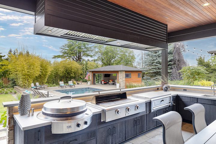 Photo of an outdoor patio kitchen next to an outdoor swimming pool