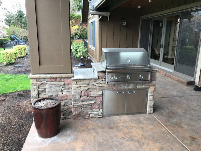 An outdated back patio with an old stainless steel gas grill