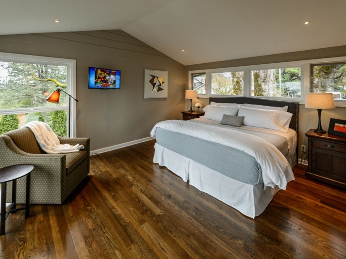A luxury bedroom featuring dark wood floors and modern furniture and a king size bed
