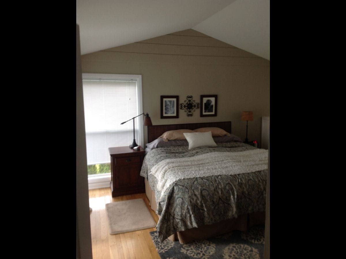 An outdated and dark bedroom with antique furniture and bed prior to remodel