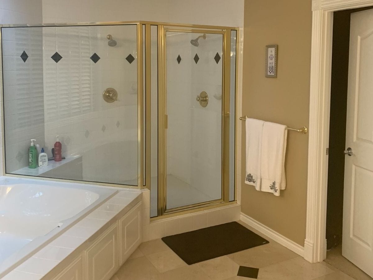 Before picture of a gray bathroom shower, showcasing the pre-renovation state with outdated features and surfaces