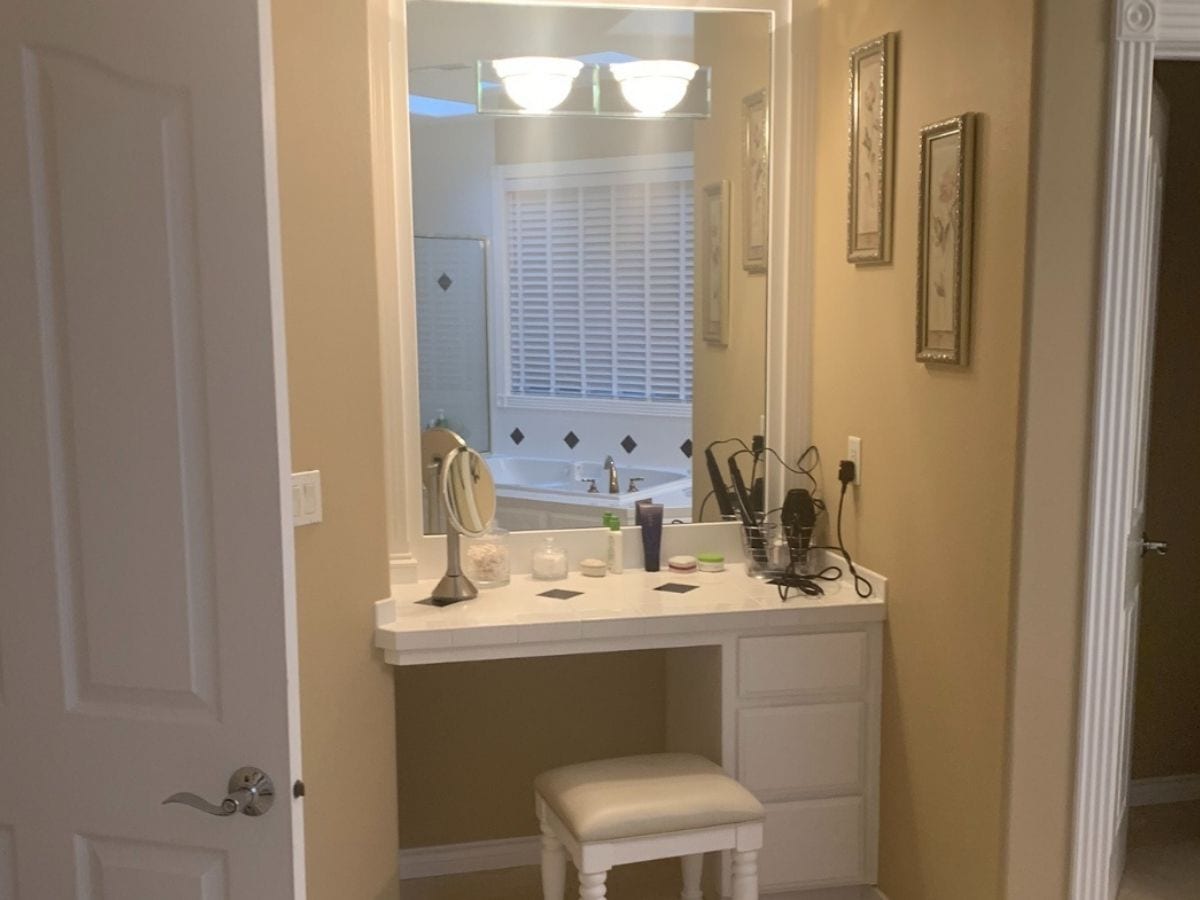 Before photo of a gorgeous gray bathroom vanity, featuring outdated fixtures and surfaces in need of renovation